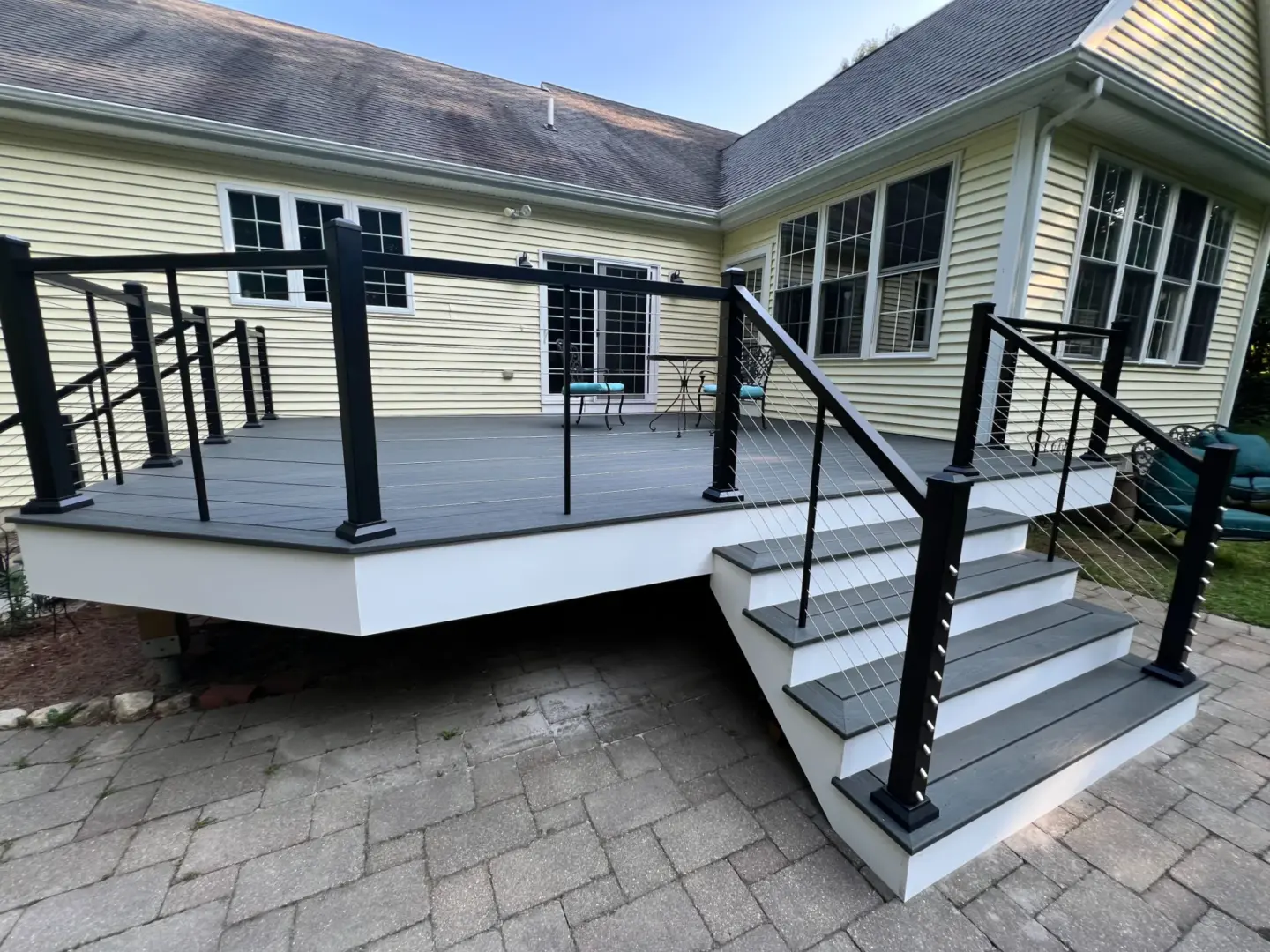 Deck with Railings Attached to a House Featuring a Window and Stairs