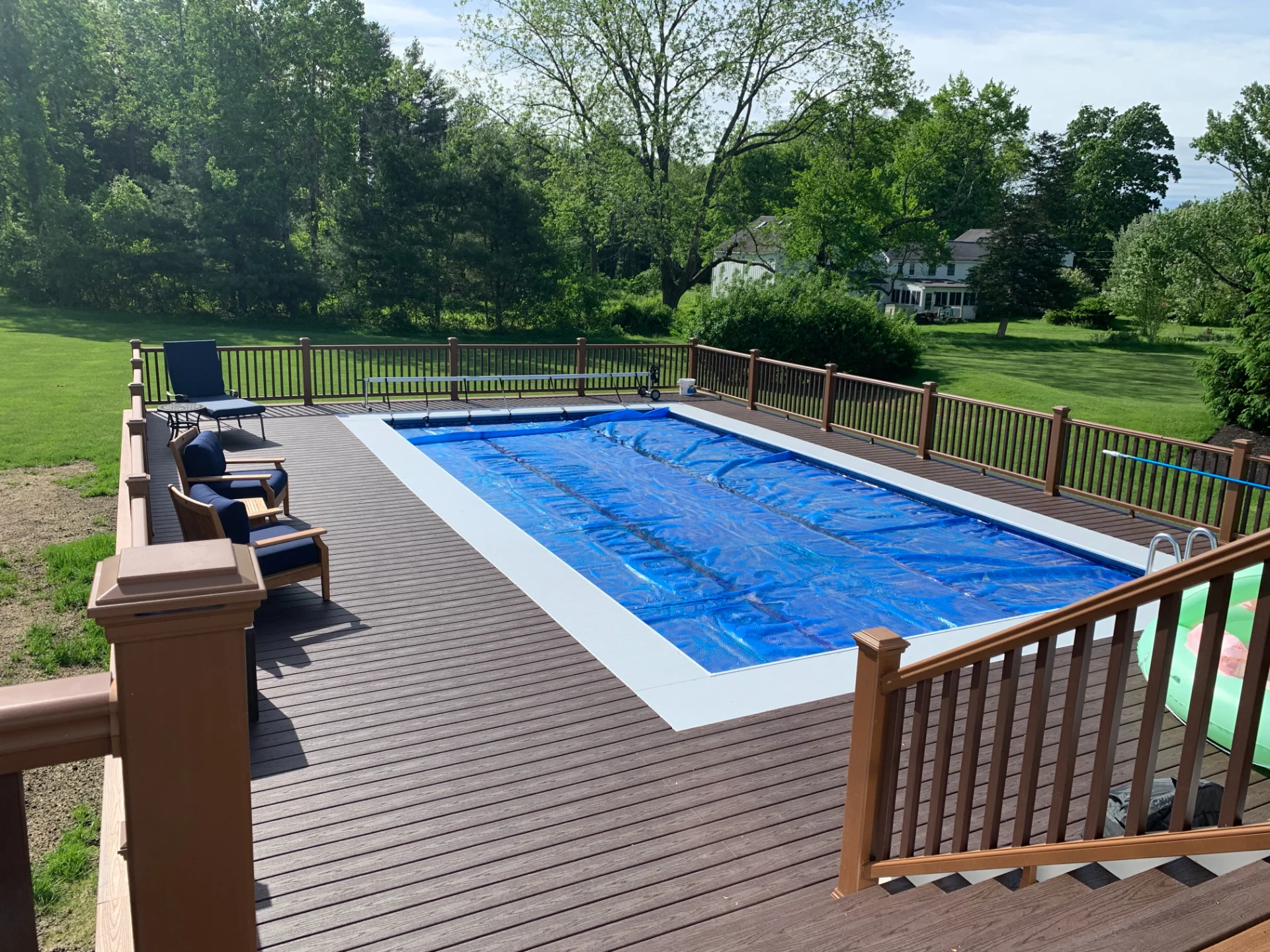Swimming Pool Situated on a Deck Surrounded by Greenery Including Trees and Plants